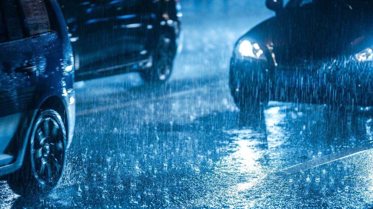 Cars driving on wet road in the rain with headlights.