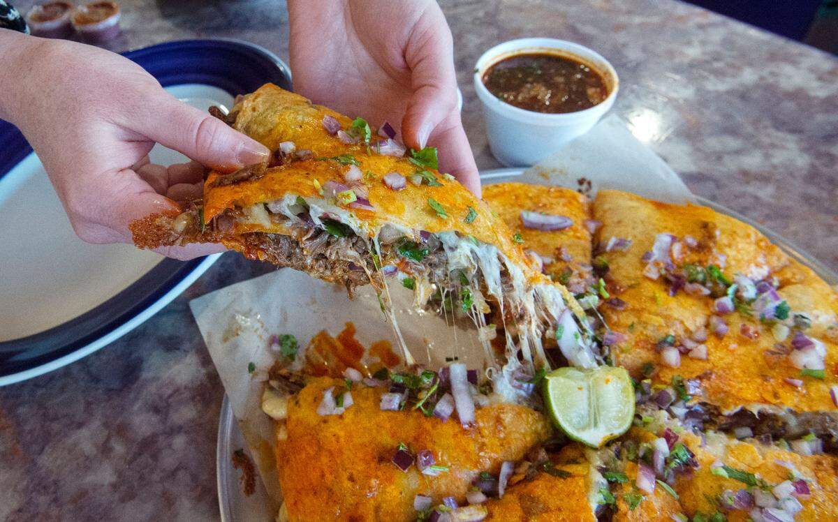 The “pizzacoa” at Los Tamales is a quesadilla-like creation featuring layers of marinated beef (barbacoa), cheese and tortillas topped with red onion, cilantro and lime.