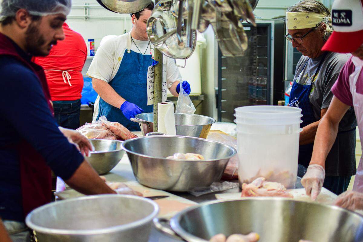 Nick Lay (left) and William Samaras (center) joined other volunteers on chicken-prep duty on Wednesday. They plan to roast 890 half-chickens over the weekend.