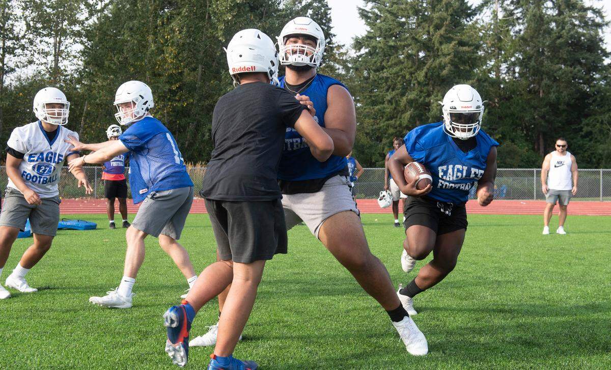 Graham-Kapowsin lineman Vega Ioane clears the way for running back Jalen Davenport during the Eagles’ football practice at Graham-Kapowsin High School in Graham, Washington, on Wednesday, Aug. 18, 2021.