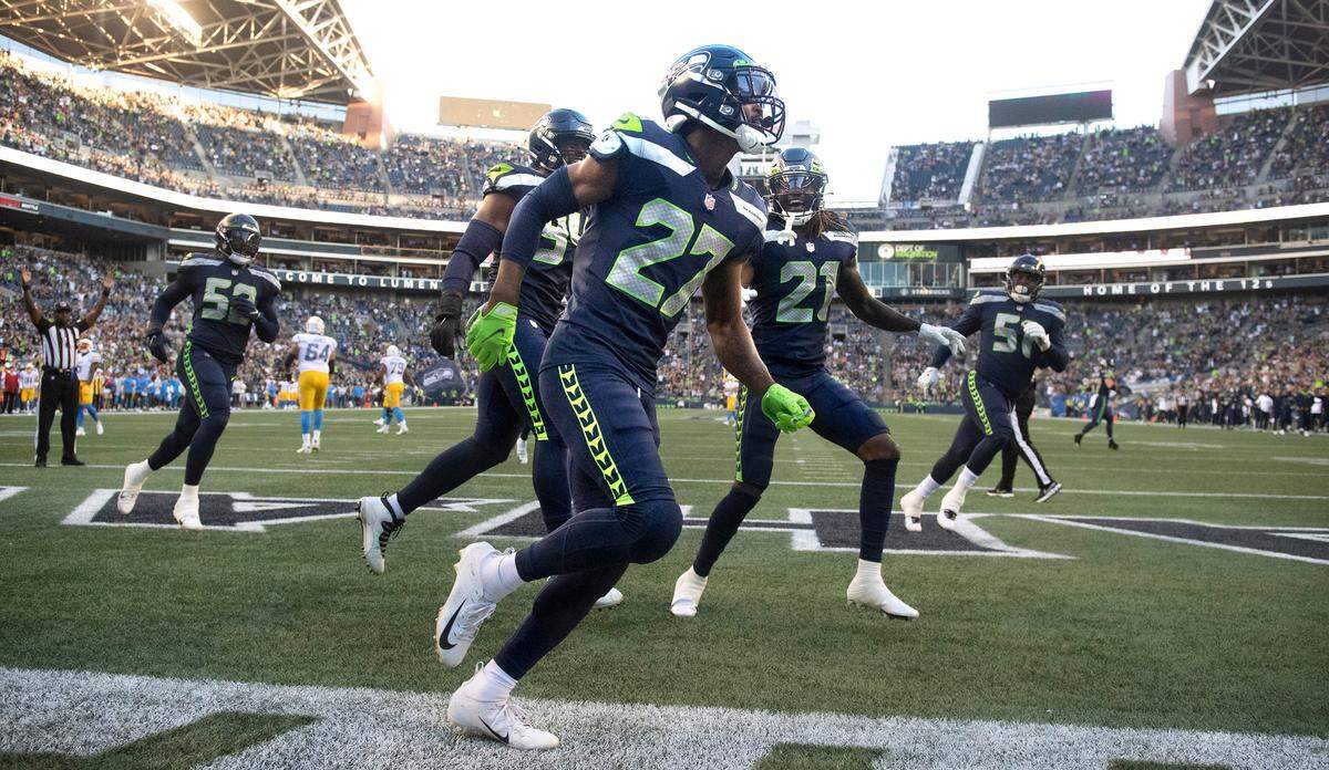 Seattle free safety Marquise Blair (27) and teammates celebrate Blair’s pick six interception to open scoring in Saturday night’s NFL preseason football game against the Los Angeles Chargers at Lumen Field in Seattle, Washington, on Aug. 28, 2021.