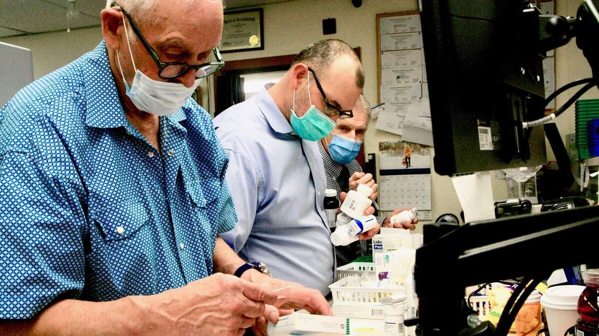 Don Zimmerman, 77, foreground, still fills prescriptions by hand two days a week at the family-owned Cost Less pharmacy in Wauna. That’s his son, Drew, at right.
