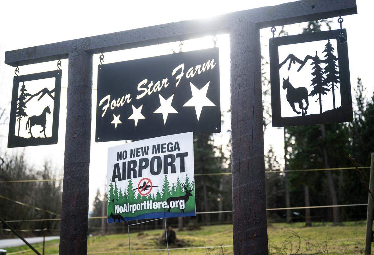 A sign opposing a new airport in Graham is positioned under Four Star Farm’s welcome sign in Graham on Jan. 31, 2023. Sharon Lulham and her daughter, Sholeh Lulham-New, are co-owners of Four Star Farms, where the nonprofit, Horses Guiding Humans, operates and helps over 50 clients receive equine-assisted mental health therapy each week.