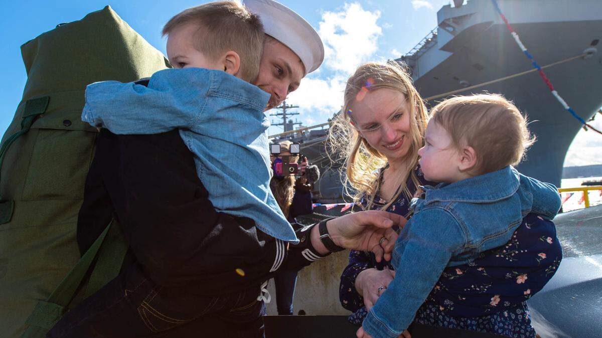 Machinist’s Mate 2nd Class Skyler Record (left), from Salt Lake City, greets his family after returning from deployment. The carrier returned to its homeport Naval Base Kitsap, Bremerton, after more than 11 months in the Mideast.