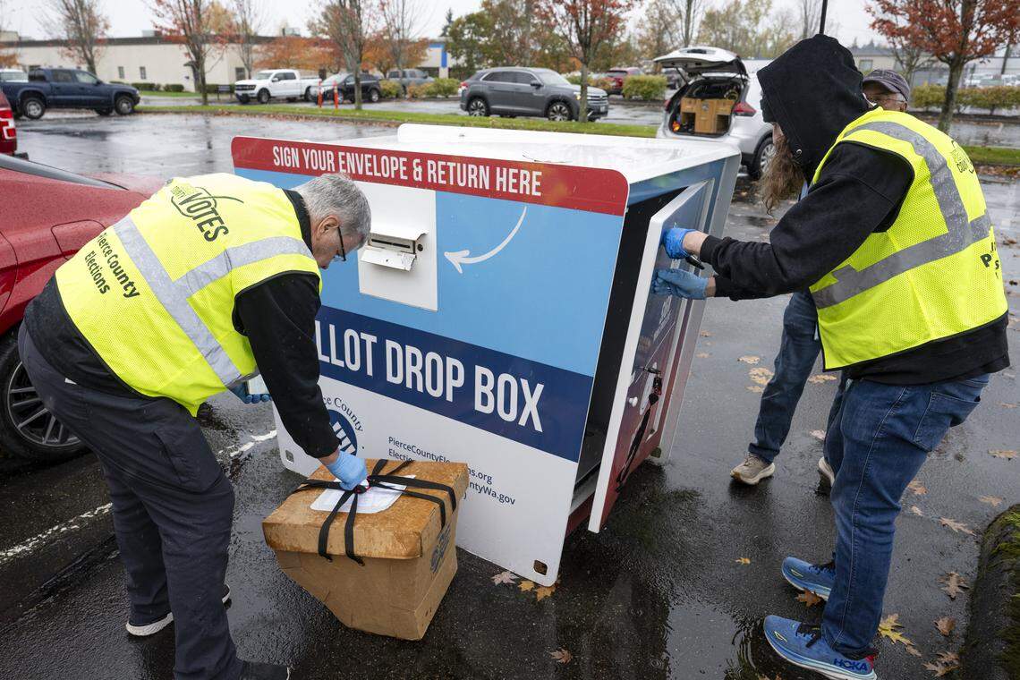 Pierce County election workers John Olsen, left, and Owen Davies collect ballots from a drop box located in the parking lot of the Pierce County Annex on Monday, Nov. 3, 2025, in Tacoma.