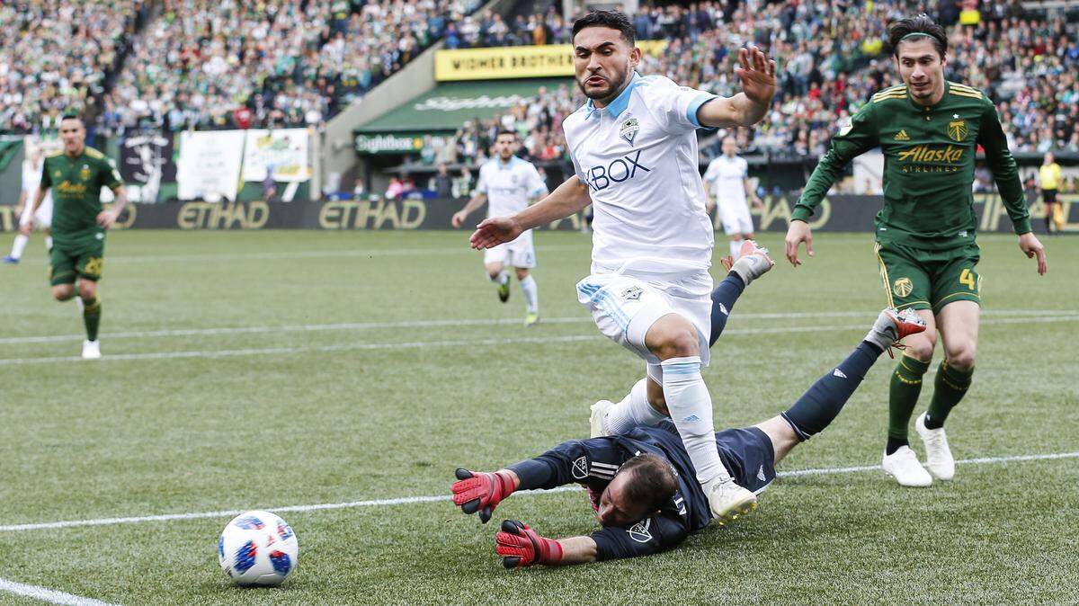 Seattle Sounders’ Cristian Roldan, top center, trips over the arms of Portland Timbers goalkeeper Jeff Attinella during an MLS soccer game in the Western Conference semifinals in Portland, Ore., Sunday, Nov. 4, 2018. (Ben Ludeman/The Oregonian via AP)