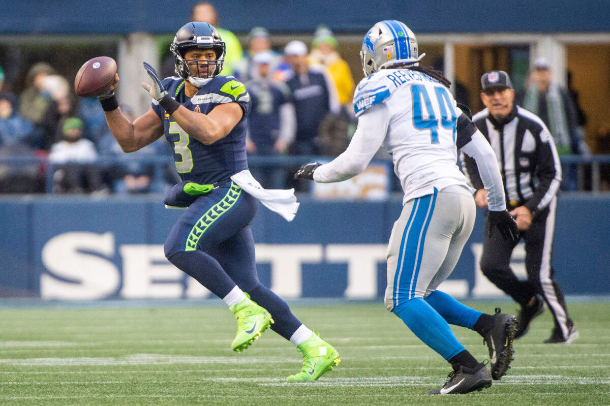 Seattle Seahawks quarterback Russell Wilson (3) scrambles out of the pocket and gives a pump fake to freeze Detroit Lions inside linebacker Jalen Reeves-Maybin (44) as he runs up field during the third quarter of an NFL game on Sunday, Jan. 2, 2022, at Lumen Field in Seattle.