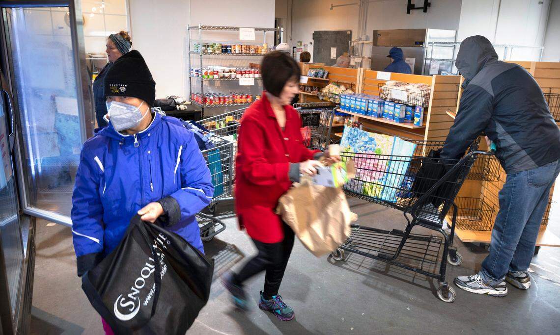 Volunteer Vicki Armstrong (center) of Lake Tapps keeps shelves stocked as shoppers visit the Sumner Community Food Bank in Sumner, Washington, on Wednesday, May 18, 2022.