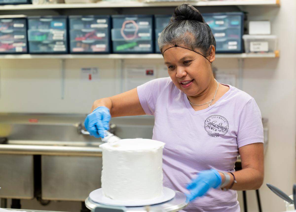 Odette D’Aniello decorates a cake at Celebrity Cake Studio in Tacoma, on Tuesday, Oct. 15. She learned the skill as a child at her family’s bakery in Guam and has operated a bakery in the South Sound since 1999.