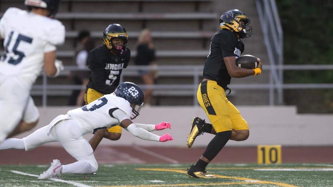 Lincoln quarterback Sione Kaho breaks loose from Gig Harbor defensive back Justin Morris for the game’s opening touchdown during Friday night’s 3A South Sound League football game at Lincoln Bowl in Tacoma, Washington, on Sept. 27, 2024.