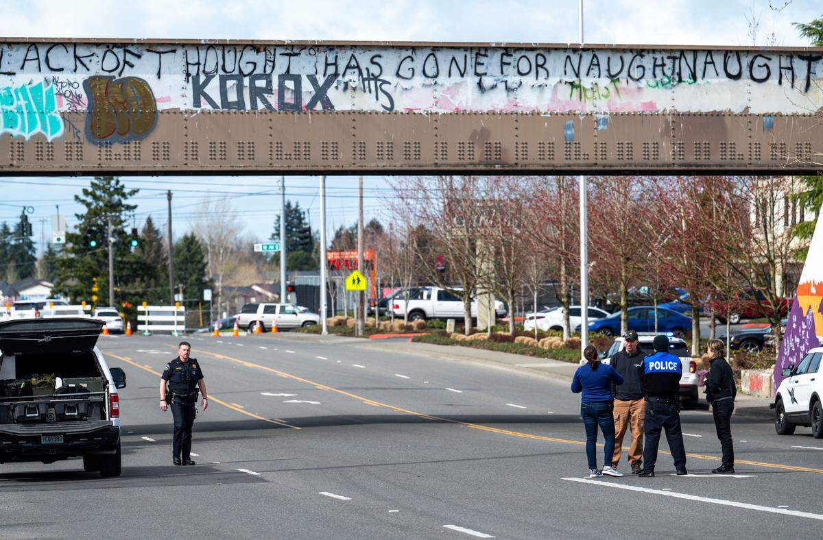 Officers investigate the scene where a man reportedly holding a grenade was shot and killed by Pierce County deputies, on the train tracks near the corner of 112th Street East and Portland Avenue in Tacoma on March 24, 2023. No officers where injured.