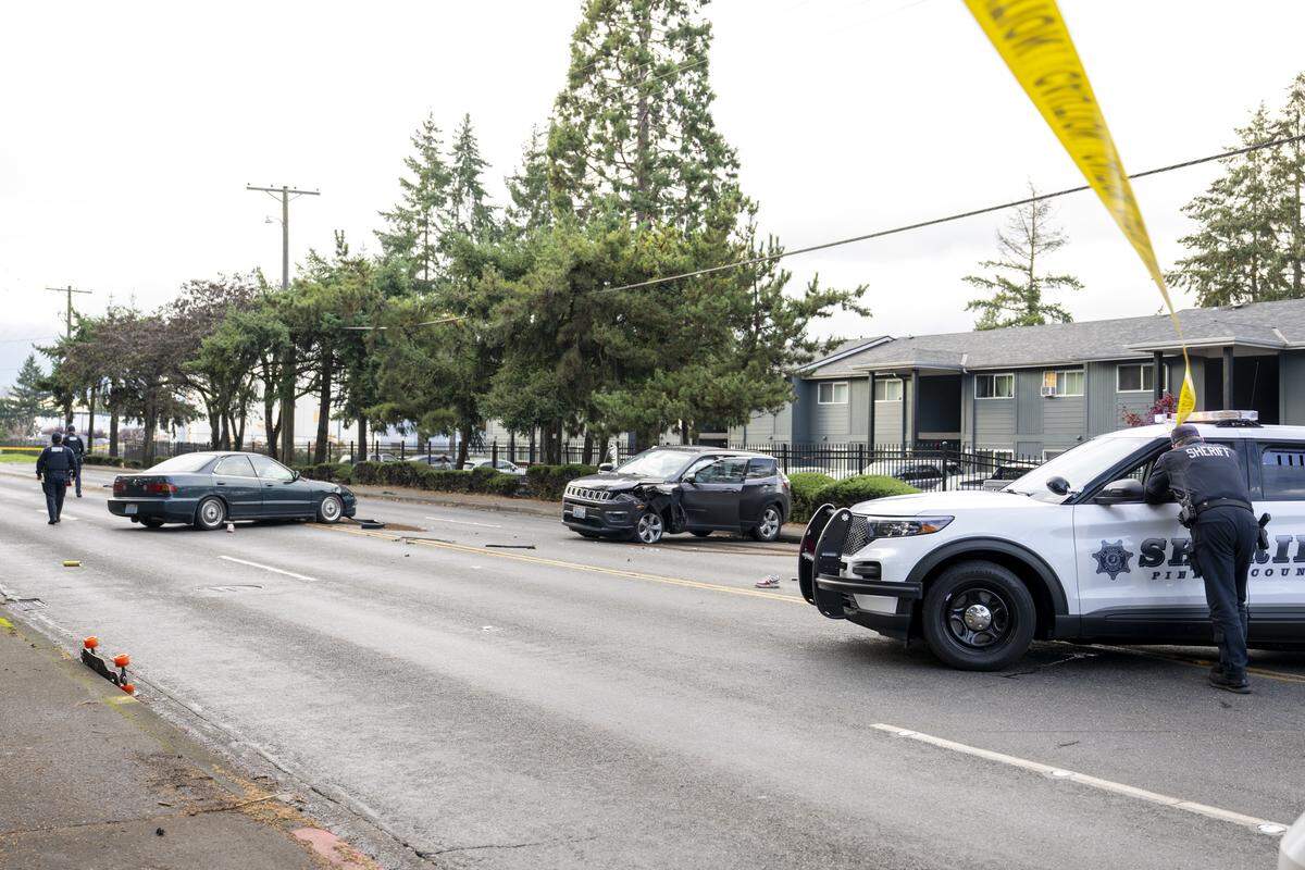 Police move about the scene where a driver struck a pedestrian and another vehicle on 96th Street South on Monday, Nov. 10, 2025, in Tacoma, Wash. Initial reporting of the crash on Monday reported two people, one on a bicycle and another on a skateboard, were struck.