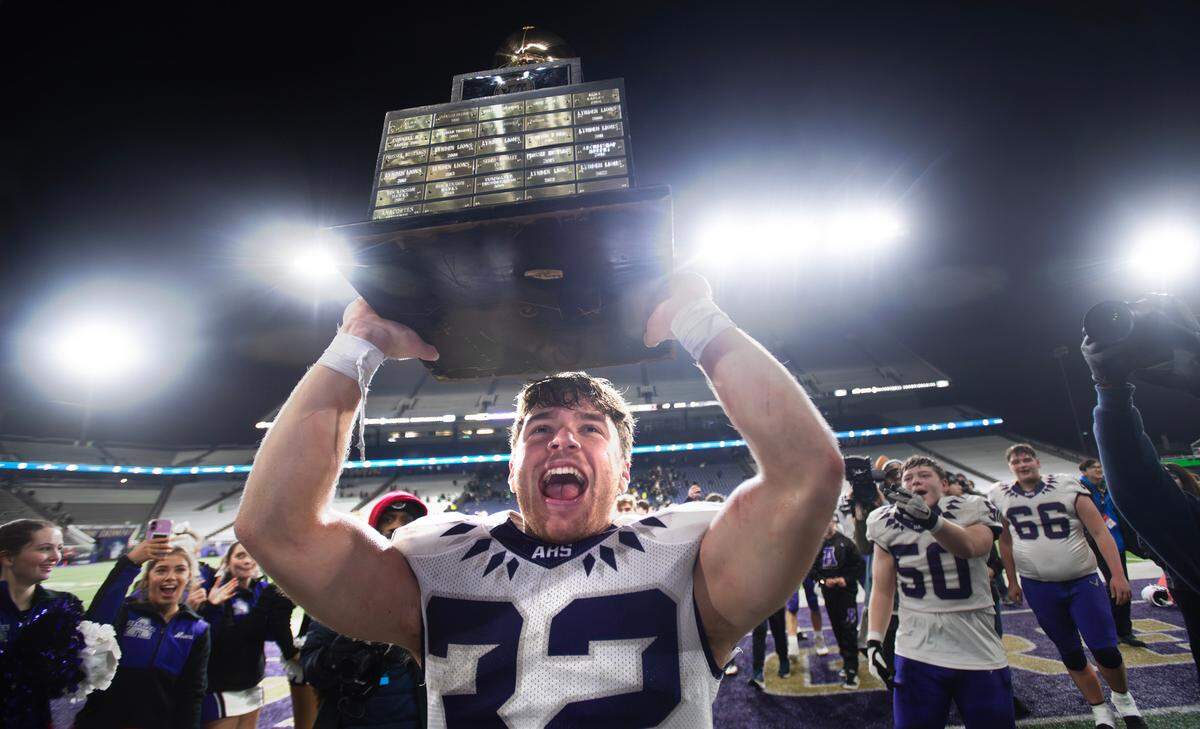 Anacortes senior running back Brock Beaner hoists the state championship trophy as the Seahawks celebrate their 20-10 victory over the Tumwater T-Birds in Saturday’s WIAA 2A state football championship game at Husky Stadium in Seattle, Washington, on Dec. 7, 2024.