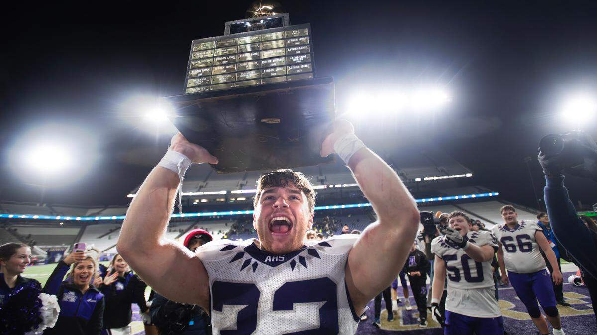 Anacortes senior running back Brock Beaner hoists the state championship trophy as the Seahawks celebrate their 20-10 victory over the Tumwater T-Birds in Saturday’s WIAA 2A state football championship game at Husky Stadium in Seattle, Washington, on Dec. 7, 2024.