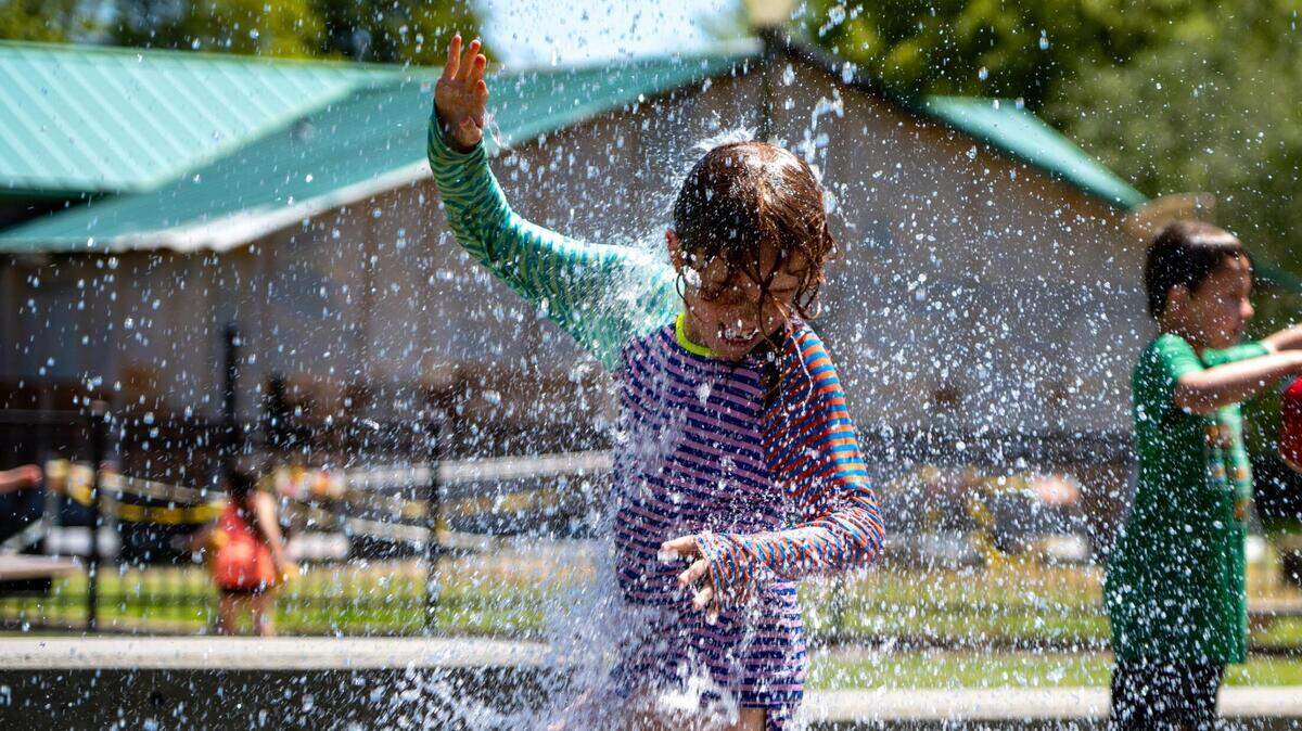 Sage Williams, 8, gets water poured on her at the sprayground at Jefferson Park in Tacoma in June 2022. Metro Parks announced Tuesday that the sprayground will be closed indefinitely for work at the park.