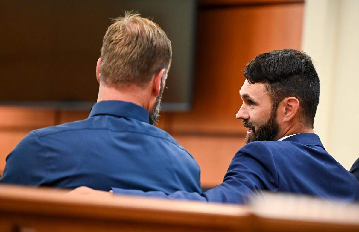 Tacoma police officers Matthew Collins and Christopher “Shane” Burbank talk in the gallery Monday during pre-trail motions in their trial in the killing of Manuel Ellis.