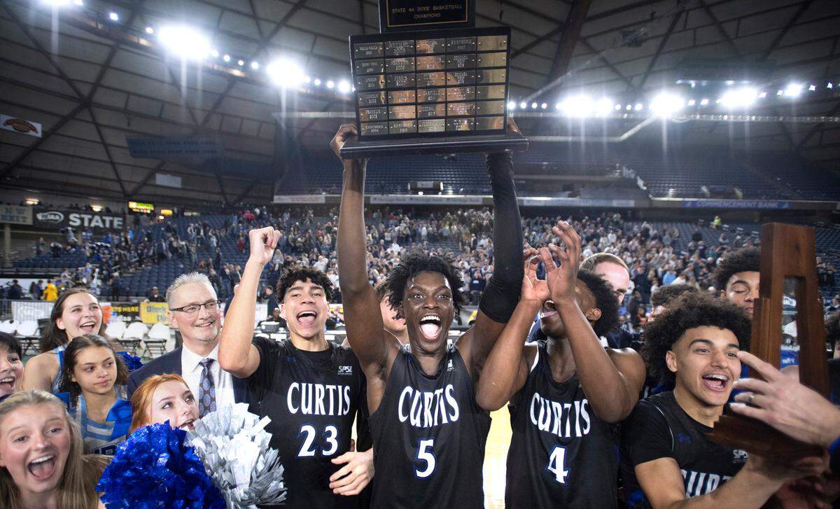 Curtis’ Zoom Diallo hoists the state championship trophy following the Vikings’ 49-43 win over the Olympia Bears in the 4A boys state title game at the WIAA state basketball tournament in the Tacoma Dome in Tacoma, Washington, on Saturday, March 4, 2023.