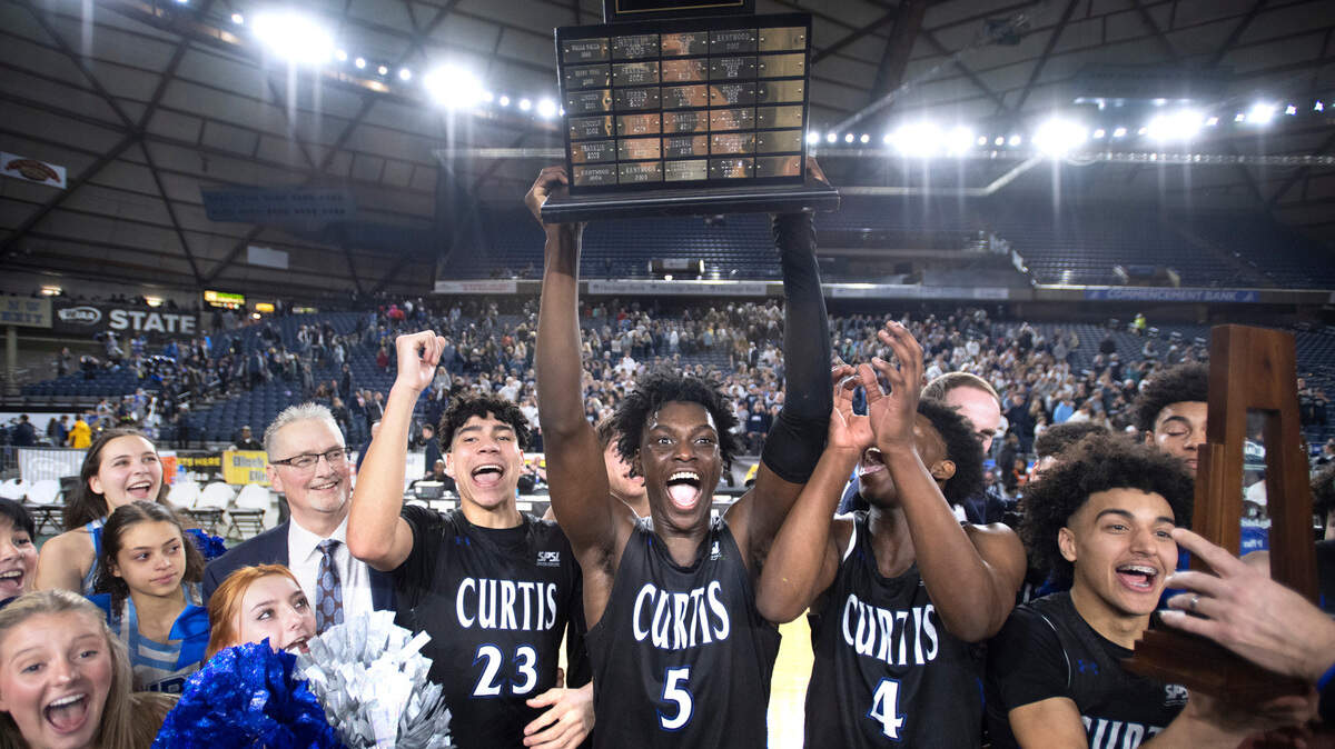 Curtis’ Zoom Diallo hoists the state championship trophy following the Vikings’ 49-43 win over the Olympia Bears in the 4A boys state title game at the WIAA state basketball tournament in the Tacoma Dome in Tacoma, Washington, on Saturday, March 4, 2023.