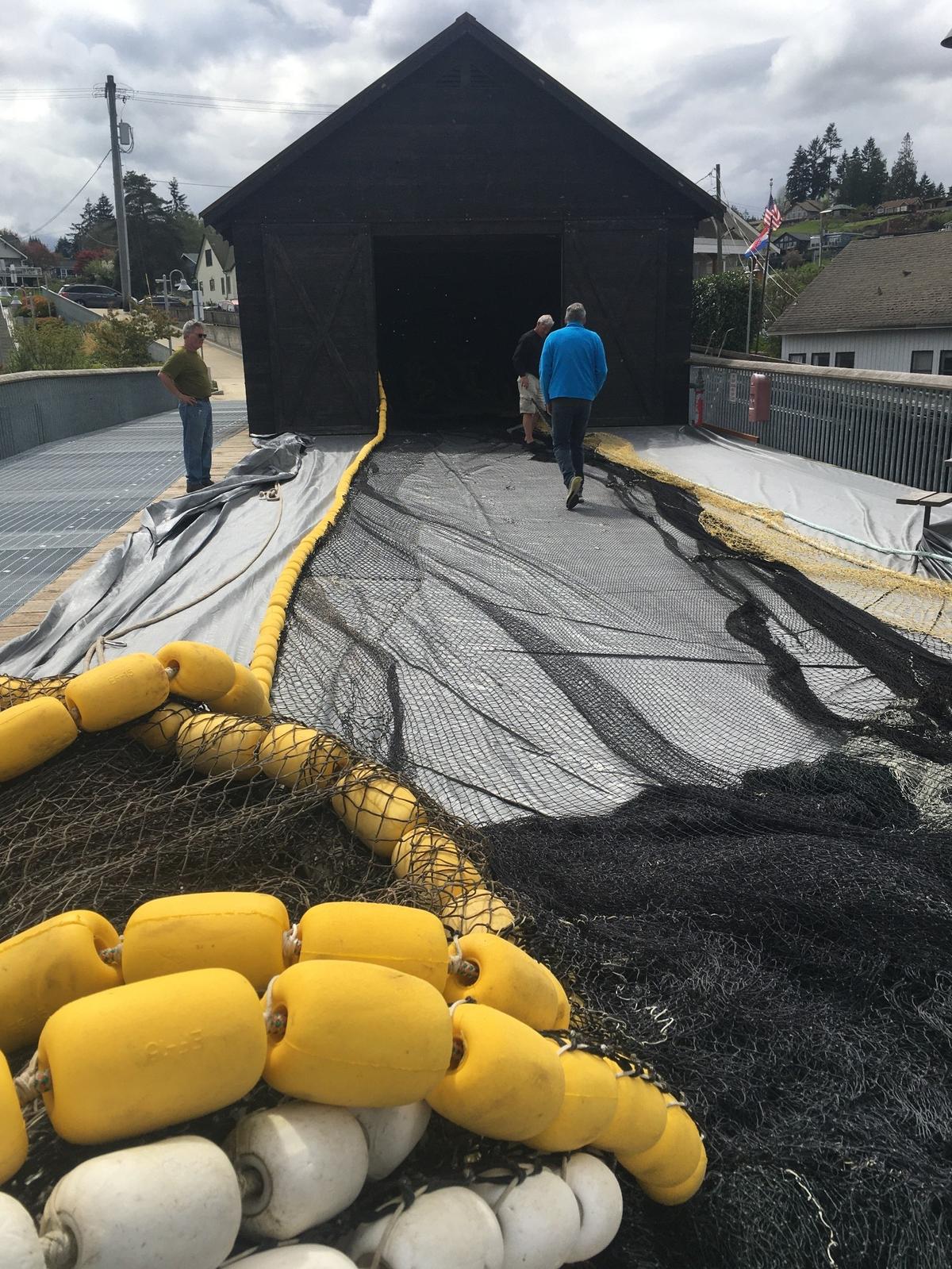 Local fishermen repair a net at the Ancich Netshed.