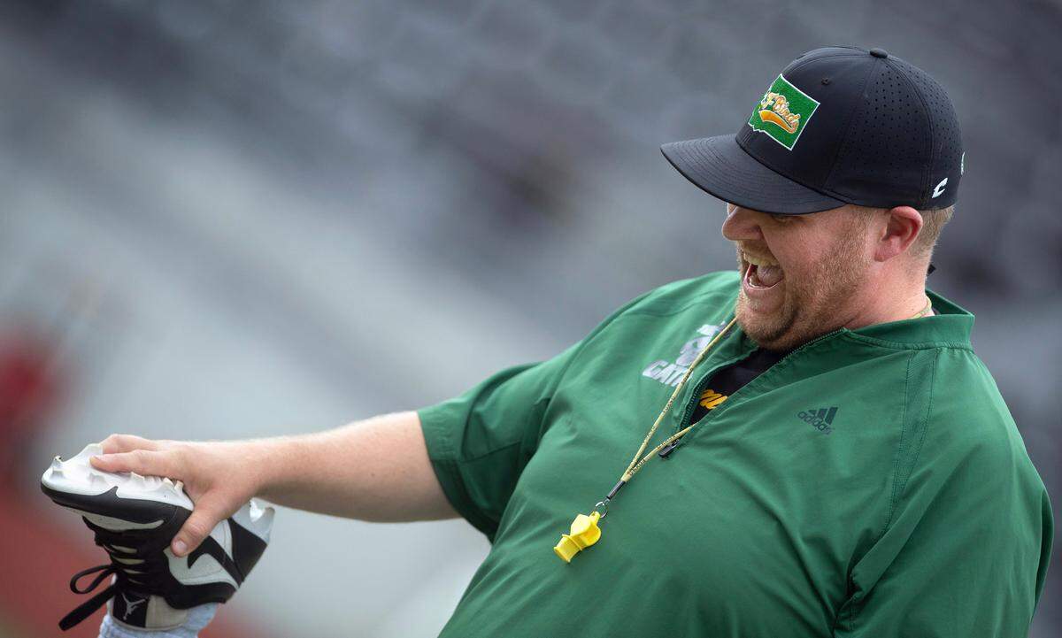 Tumwater head coach William Garrow laughs with a T-Bird player during preseason football practice at Tumwater District Stadium in Tumwater, Washington, on Thursday, Aug. 22, 2024.