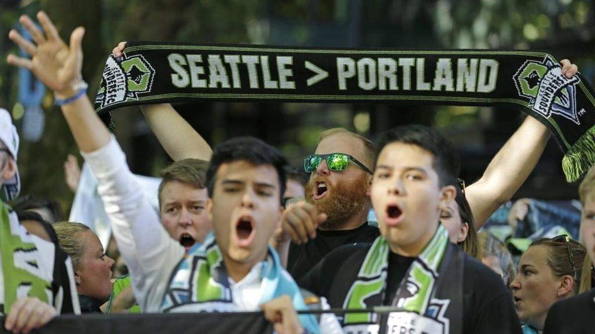 FILE - In this Aug. 27, 2017, file photo, a Seattle Sounders supporter holds up a scarf as he takes part in the traditional March to the Match before an MLS soccer match against the Portland Timbers in Seattle. The Timbers host the Sounders on Sunday in the 100th meeting between the two rivals from the Pacific Northwest. (AP Photo/Ted S. Warren, File)