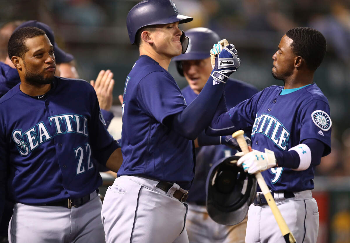 Seattle Mariners’ Ryon Healy, center, celebrates with Dee Gordon, right, as Robinson Cano (22) watches after Healy hit a two-run home run off Oakland Athletics’ Mike Fiers during the fourth inning of a baseball game Friday, Aug. 31, 2018, in Oakland, Calif. (AP Photo/Ben Margot)