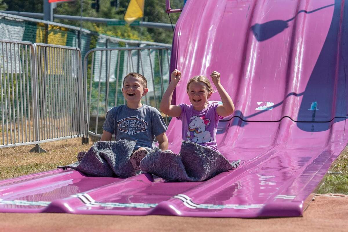 Henry, 11, and Lizzie R., 9, race down the big slide at the 75th anniversary of the Pierce County Fair in Graham, Wash. on Aug. 11, 2022.