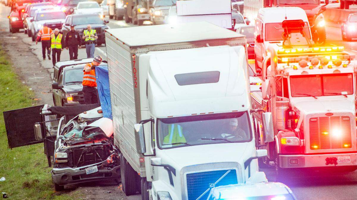Bumper-to-bumper traffic surrounds a tow truck driver who lifts a tarp atop a truck that was involved in a fatal collision on southbound Interstate 5 north of South 84th Street in Tacoma, Wash., on Tuesday, Feb. 15, 2022. The driver of the work truck rear-ended the semi-truck which was slowing down due to another collision ahead. The driver of the work truck was extracted from the vehicle, but declared dead on the scene.