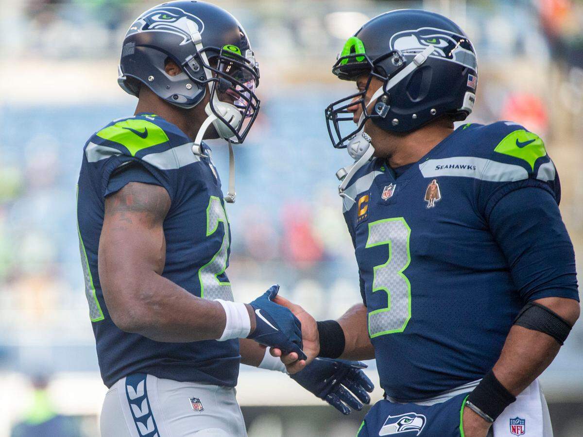 Seattle Seahawks running back Adrian Peterson (21) and quarterback Russell Wilson (3) shake hands prior to the start of an NFL game against against the San Francisco 49ers on Sunday at Lumen Field in Seattle.