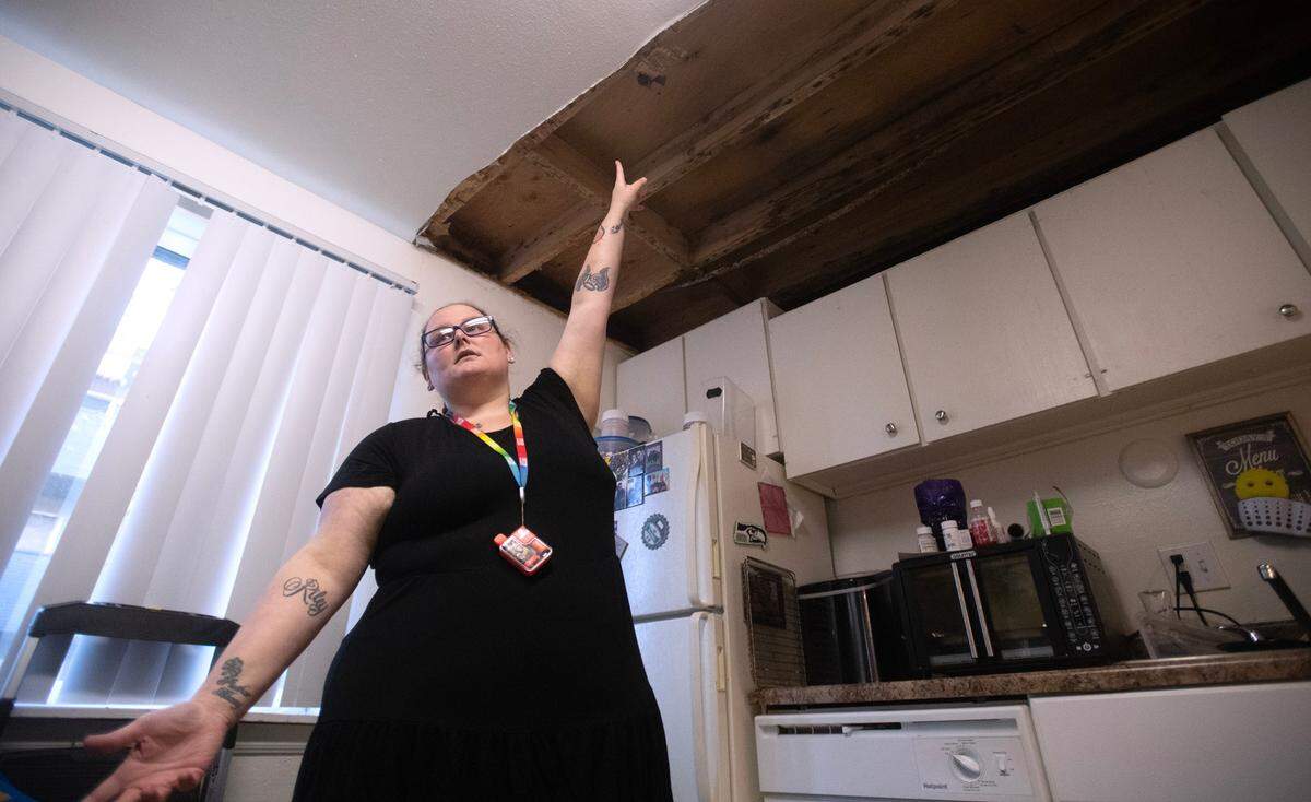 Cassie Morrone shows the water damage in the ceiling and walls of the kitchen in the first-floor apartment where she lives with her husband and children at the Legacy Park Apartments in Lakewood, Washington, on Wednesday, Nov. 8, 2023.