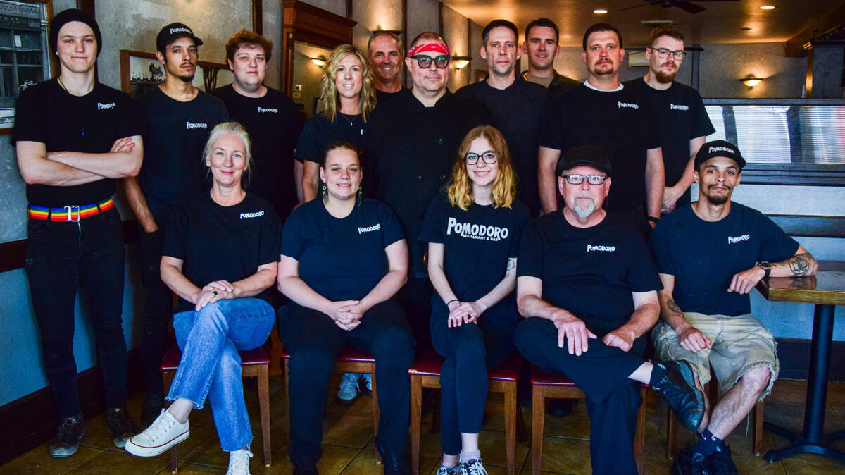 Pomodoro owner Erin Behnke (back row, fourth from left) preferred to have her photo taken last Saturday with her staff, including multiple generations of the same family and many employees of more than 20 years. The restaurant will close after service on July 30.