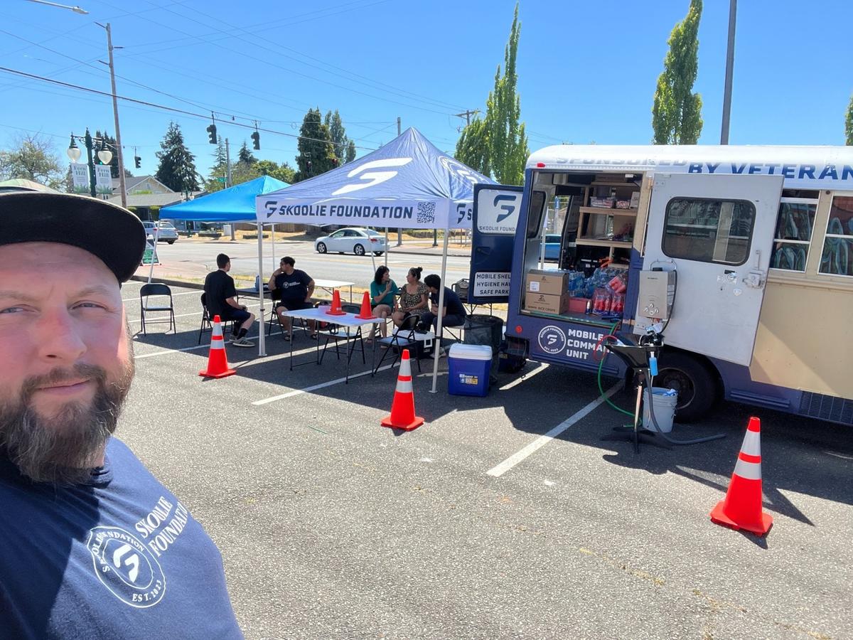 Skoolie Foundation board chair Brandon Simmons takes a selfie in front of the Mobile Command Unit at the Fern Hill Library in Tacoma on Tuesday, July 9, 2024.