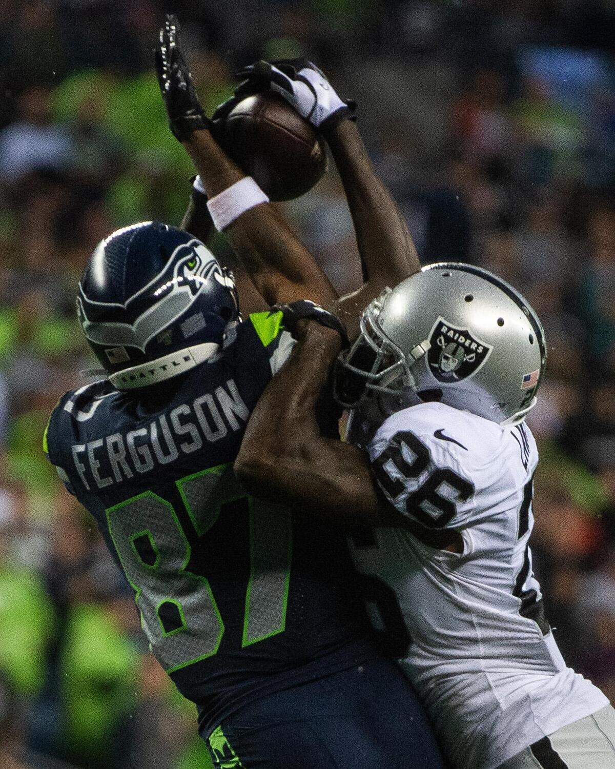 Seattle Seahawks wide receiver Jazz Ferguson (87) makes a catch over Oakland Raiders cornerback Nevin Lawson (26) during the second quarter. The Seattle Seahawks played the Oakland Raiders in a National Football League game at CenturyLink Field in Seattle, Wash., on Thursday, Aug. 29, 2019.