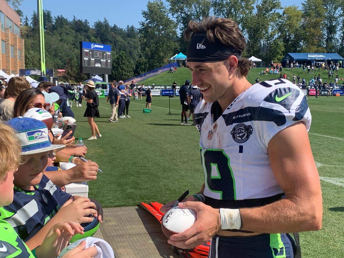 Wide receiver Jake Bobo with a jersey bloodied by teammate Tre Brown’s punch signs autographs for fans following the contentious 13th practice of Seattle Seahawks training camp at the Virginia Mason Athletic Center, Aug. 7, 2024. Bobo got a cut on the bridge of his nose from Brown’s punch, after the cornerback pulled Bobo’s helmet off at the end of a play.