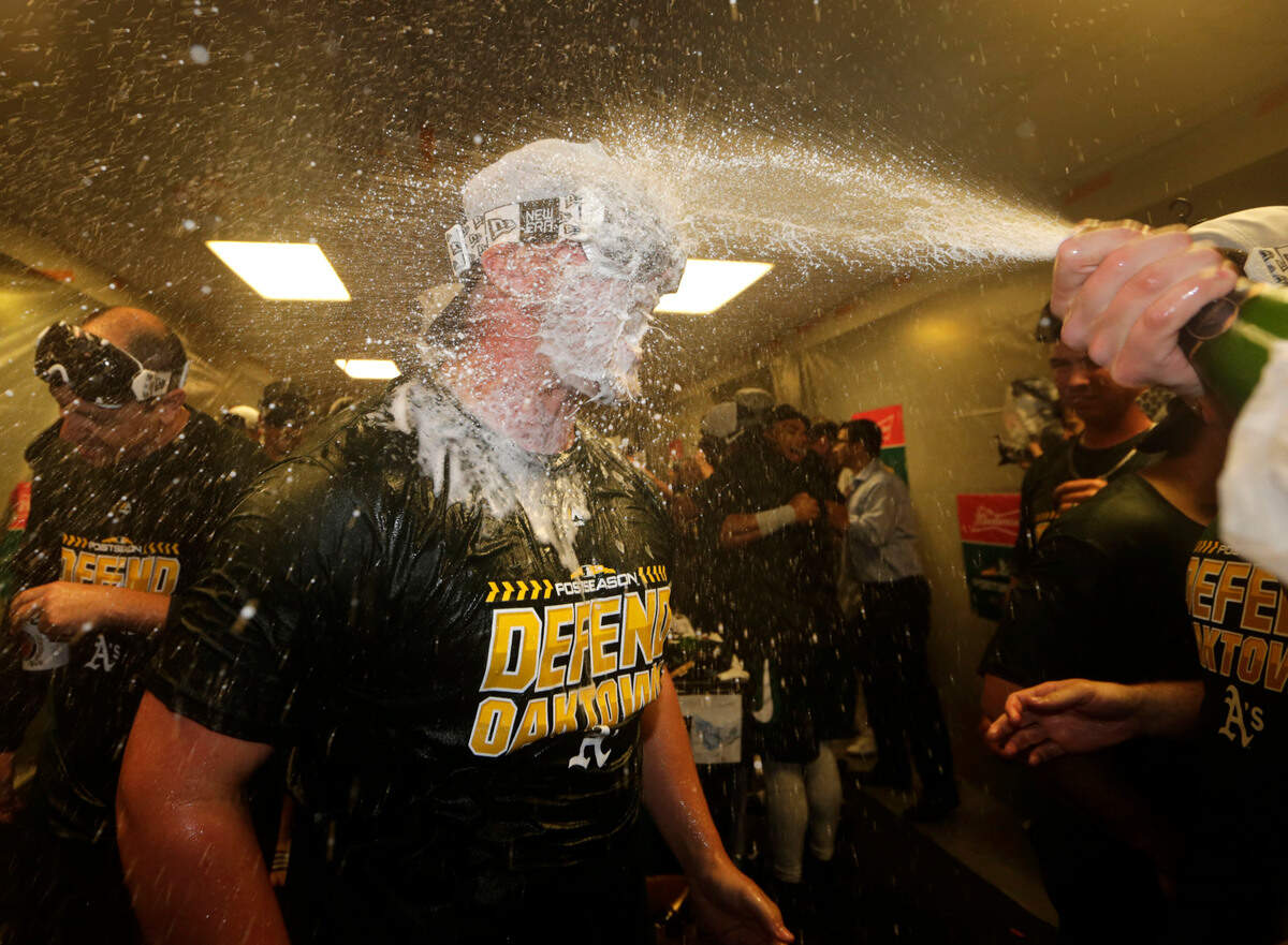 Oakland Athletics’ J.B. Wendelken is doused in the clubhouse celebration after clinching a wild card spot after the baseball game against the Seattle Mariners, Monday, Sept. 24, 2018, in Seattle. (AP Photo/John Froschauer)