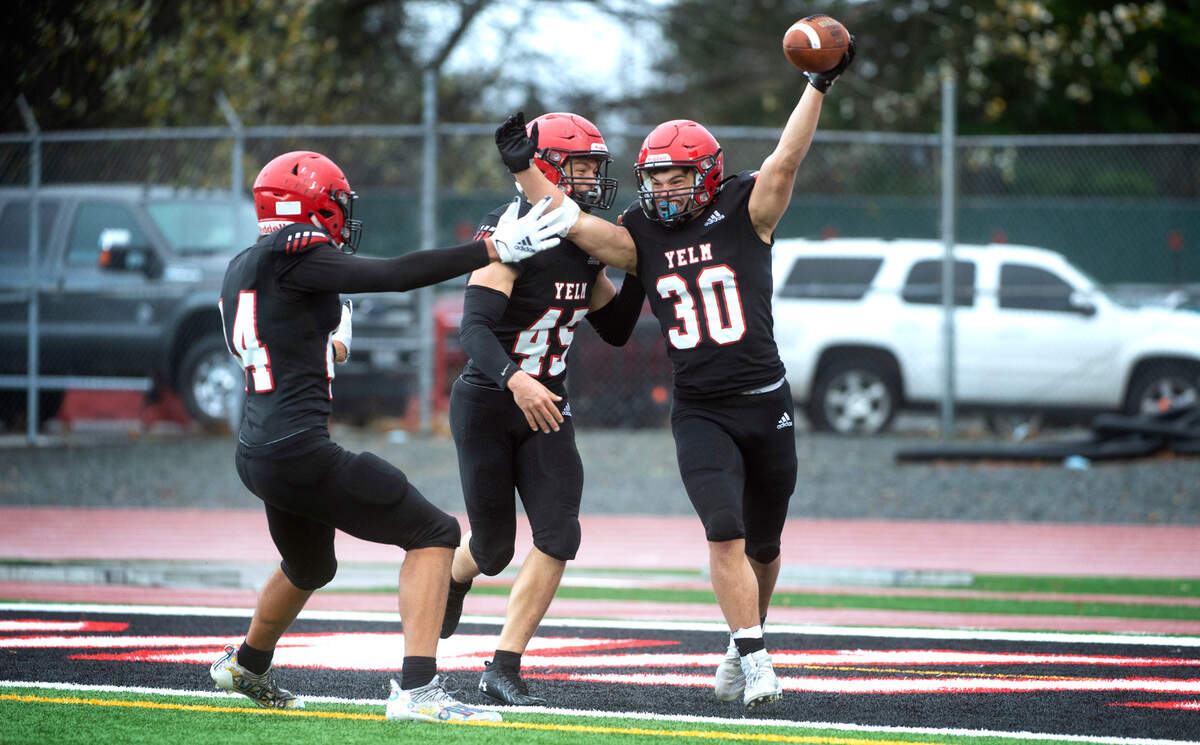 Yelm linebacker William Carreto (30) celebrates with teammates Onyx Carter and Dylan Conklin (45) following Carreto’s pick-six interception of Mead quarterback Colby Danielson during Saturday afternoon’s high school football playoff game at Yelm High School in Yelm, Washington, on Nov. 6, 2021. Yelm won the game, 37-21.