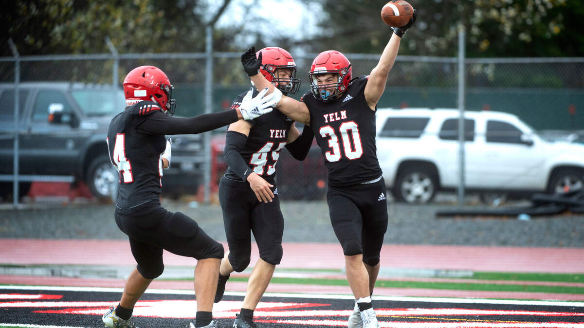 Yelm linebacker William Carreto (30) celebrates with teammates Onyx Carter and Dylan Conklin (45) following Carreto’s pick-six interception of Mead quarterback Colby Danielson during Saturday afternoon’s high school football playoff game at Yelm High School in Yelm, Washington, on Nov. 6, 2021. Yelm won the game, 37-21.