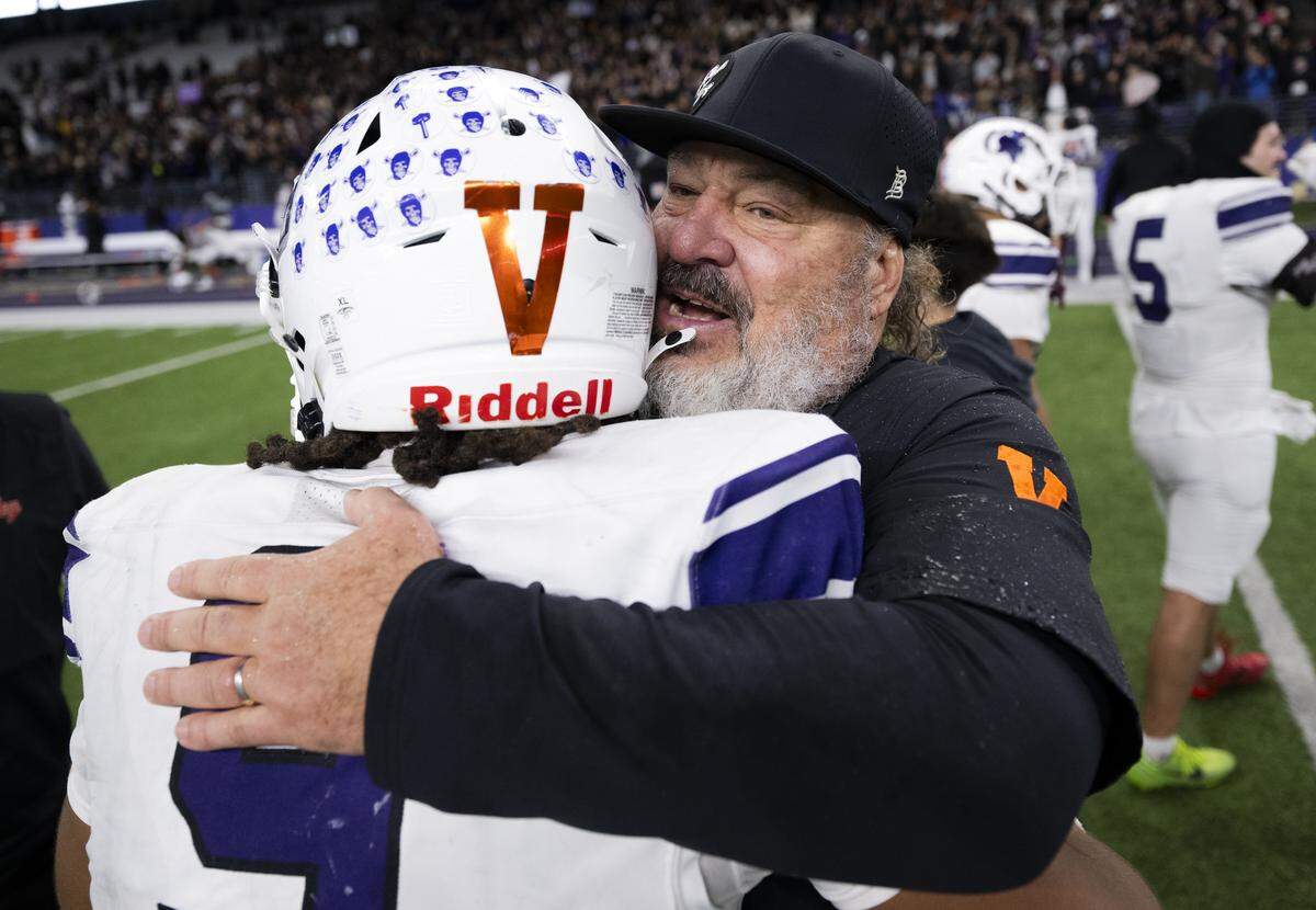 Sumner running back Lance McGee (9) and head coach Keith Ross embrace after Sumner’s 41-35 victory against Lake Stevens in the 4A State Championship game at Husky Stadium, on Saturday, Dec. 6, 2025, in Seattle.