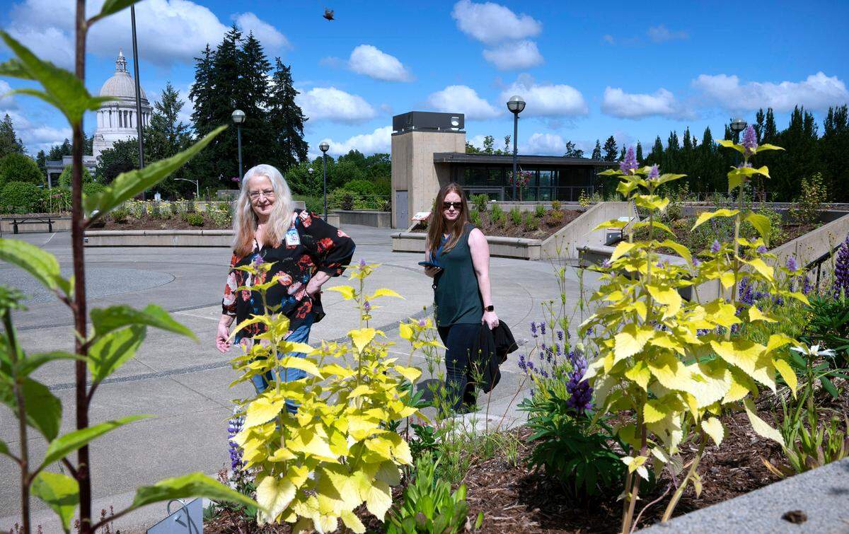 State workers Patty Boyer (left) of Lacey and Rachel Robbie of Olympia visit the Capitol Campus Pollinator Garden on the East Capitol Campus in Olympia, Washington on Thursday, June 30, 2022. Boyer said she researches and plants butterfly- and bee-friendly flowers in her home garden.