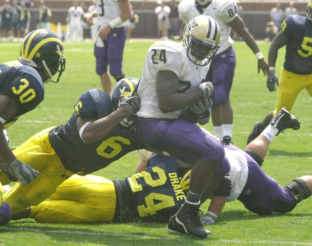 Washington back Rich Alexis (24) is stopped by Michigan linebacker Victor Hobson (6) during the second quarter at Michigan Stadium in Ann Arbor, Mich., Saturday, Aug. 31, 2002. Alexis ran for 98 yards and two touchdowns. (AP Photo/Carlos Osorio)