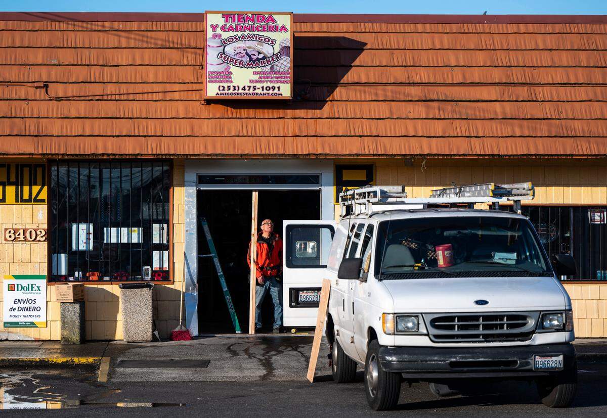 A man works on repairing a doorway that was broken during a burglary that left an employee shot and injured at Los Amigo Supermarket on South Tacoma Way in Tacoma, Wash. on Nov. 17, 2022.