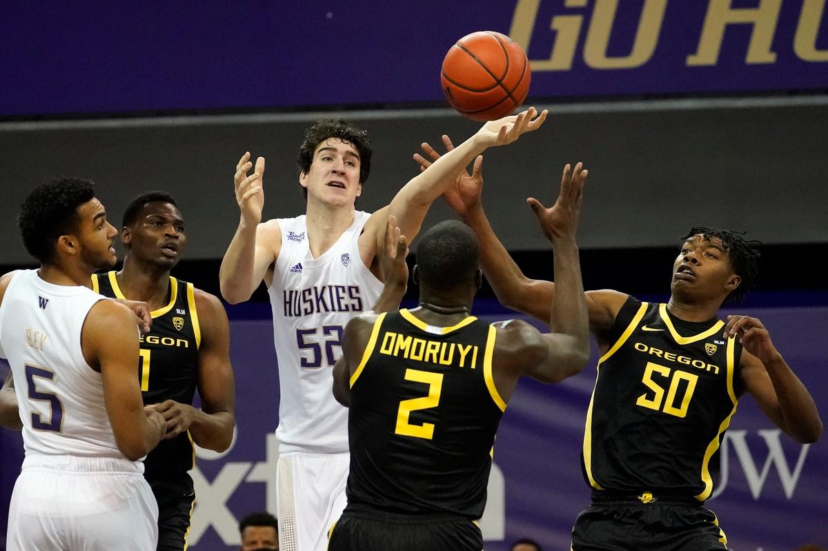 Washington’s Riley Sorn (52) reaches for the ball between Oregon’s Eric Williams Jr. (50), Eugene Omoruyi (2) and N’Faly Dante (1) as Washington’s Jamal Bey (5) watches during the first half of an NCAA college basketball game Saturday, Dec. 12, 2020, in Seattle. (AP Photo/Elaine Thompson)
