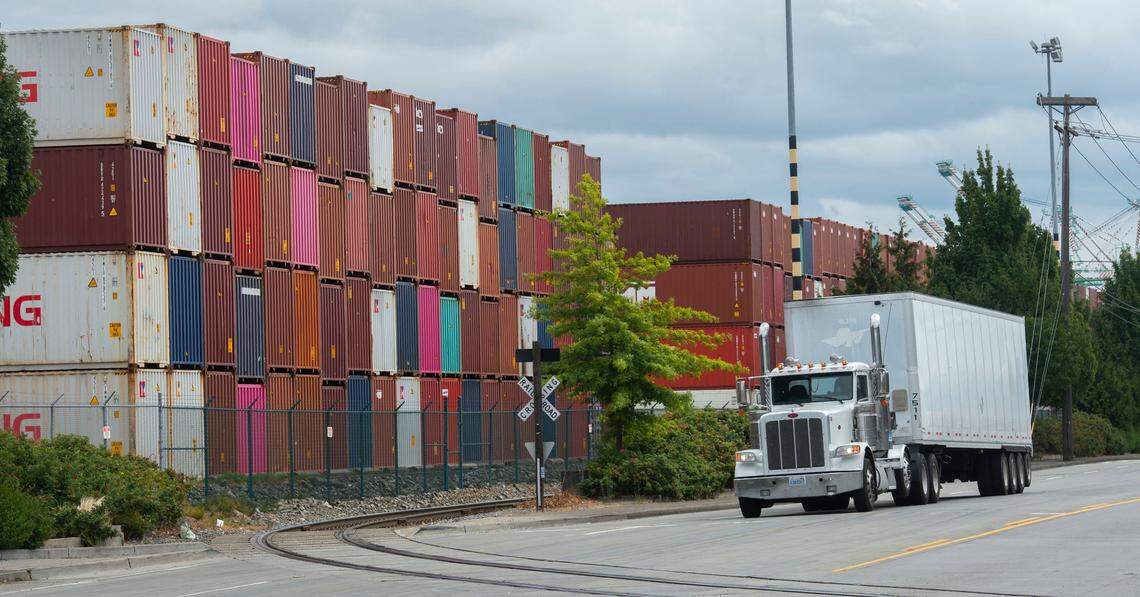 A truck cruises past a mountain of shipping containers at Washington United Terminals at the Port of Tacoma on Thursday, August 26, 2021. Many ships, already running behind schedule because of congestion at the ports, decided to leave their empty containers behind rather than wait days to load them back onboard.