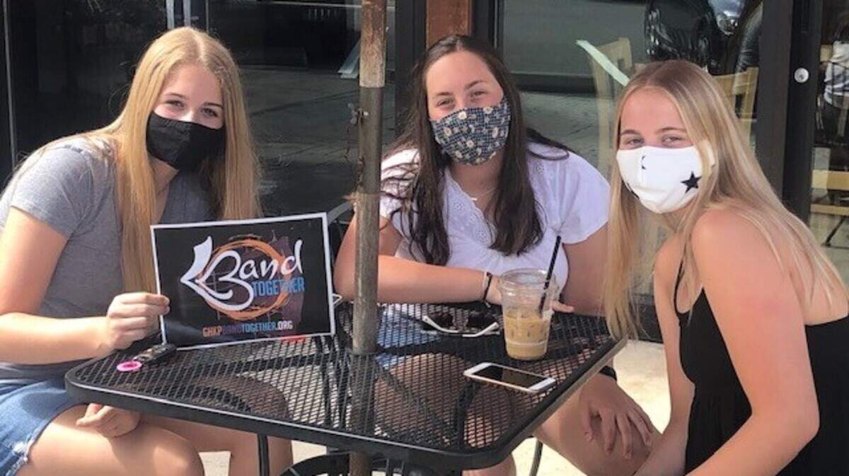 Three unidentified fans, properly masked, are ready for Band Together concerts.