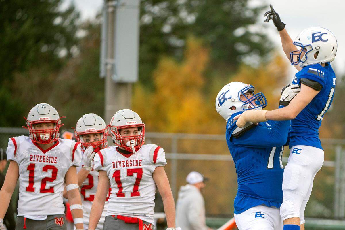 Riverside defenders look on as Eatonville offensive lineman Kyle Cox gives receiver Job Kralik a celebratory lift after his second-quarter touchdown in a State 1A quarterfinal game on Saturday afternoon at Art Crate Field in Spanaway.