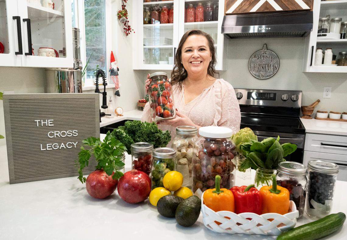 Amy Cross, founder of The Cross Legacy, poses for a portrait with some produce that she has preserved for over three weeks at her home in Bonney Lake, Wash. on Dec. 7, 2022. Amy has amassed over 140,000 followers over the course of a year from sharing tips on social media platforms and her blog about how to preserve food and fresh produce to save money on groceries.