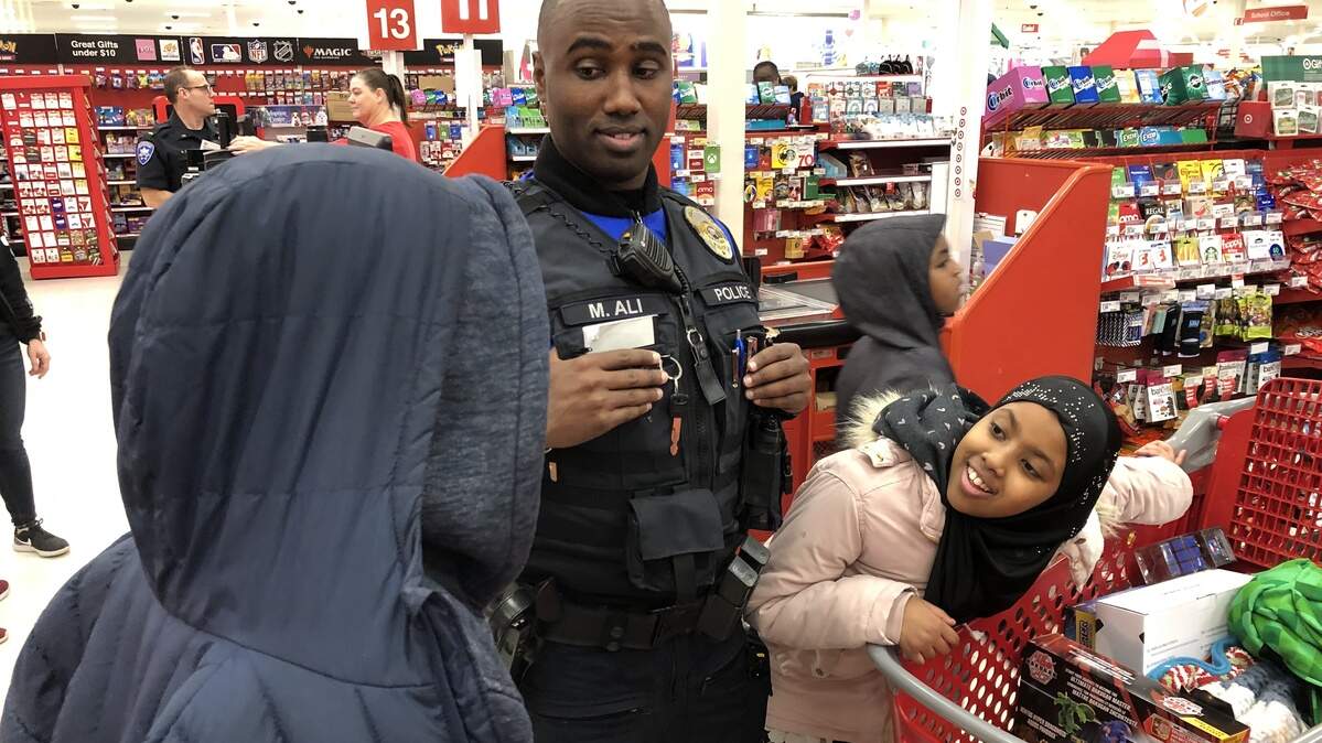 Tacoma police officer Mohamud Ali and his niece, Yasmin, 9, talk with Joshua, 9, as they wait to purchase over $200 of gifts Joshua picked out for his family at a Tacoma Target store Saturday morning during the annual Shop with a Cop.