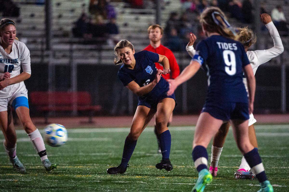 Gig Harbor midfielder Lily Paulson (center) takes a shot on goal as Auburn Riverside defender McKenzie Emmons (left) tries to block it during the second half of the District 3/4 girls soccer championship game on Thursday night at South Sound Stadium in Lacey. Paulson would score on the shot which tied the game at 1-1.