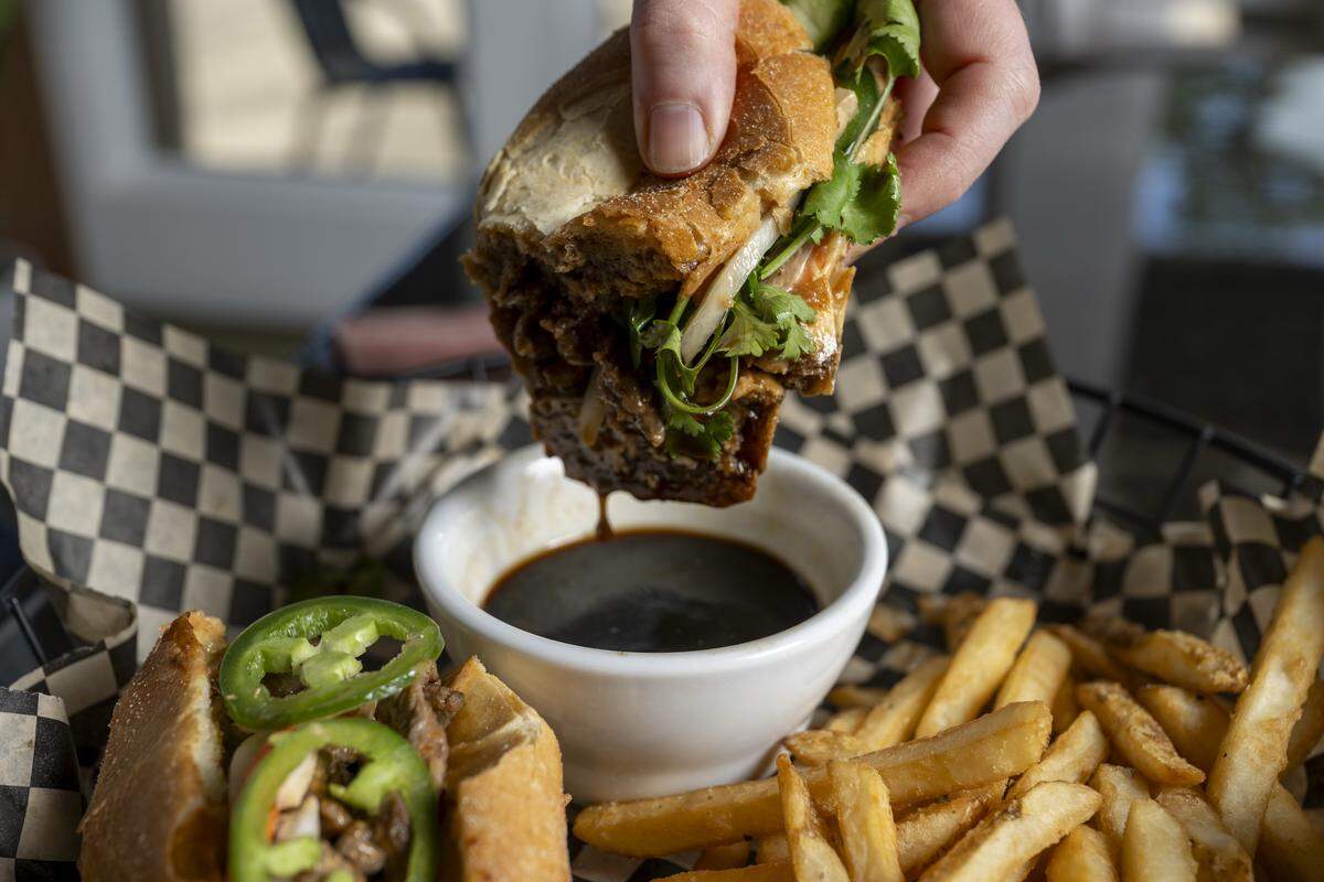 A Banh Mi Dip is dipped in seasoned broth at The Edit Social House on Thursday, May 21, 2026, at the Oakbrook Golf Club in Lakewood, Wash.