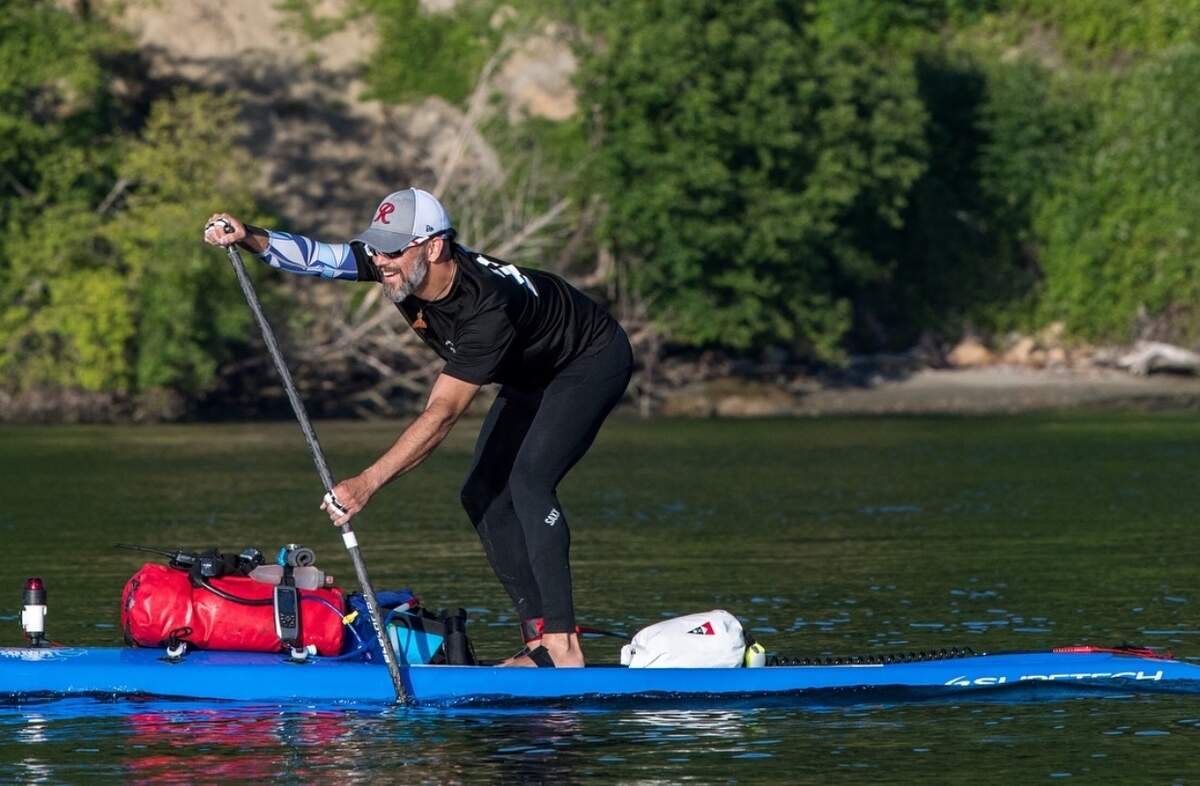 Dean Burke paddles a stand up paddleboard in frigid Puget Sound waters in stretchy pants and a rash guard.